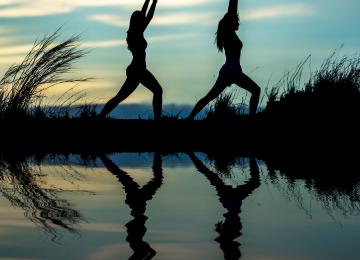 dos deportistas practicando yoga al aire libre