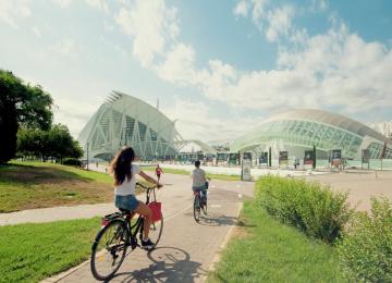 jardin del turia con fondo de ciudad de las artes y chicos con bicicletas